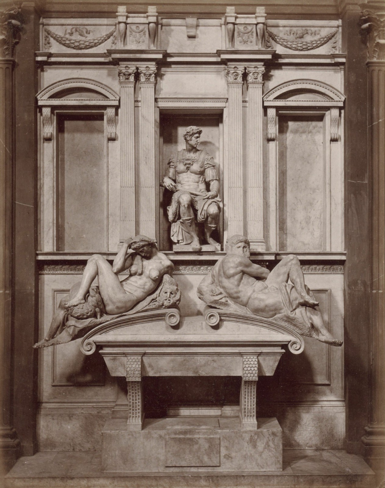 A Medici tomb by Michelangelo: a seated duke in a niche above a sarcophagus, with two reclining marble figures on its lid.