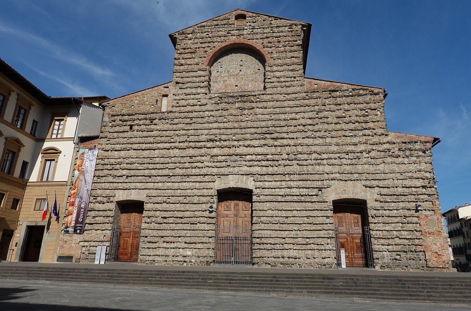 The front of the church of San Lorenzo in Florence, a plain wall of rough brown brick with three doors and no decoration.
